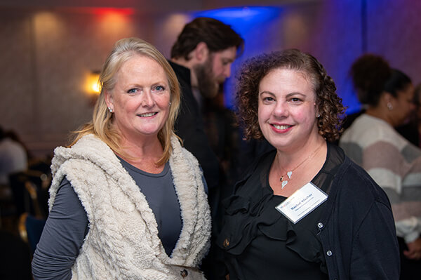 Two USALLIANCE Financial employees standing together and smiling at a company event.