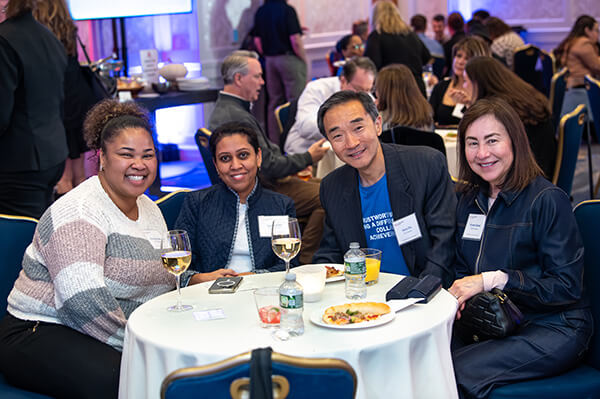 Four USALLIANCE Financial employees sitting together and smiling at a company event.
