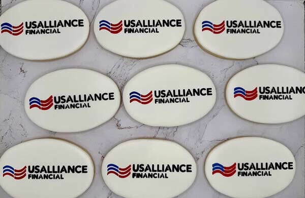 Nine round decorated sugar cookies each printed with the USALLIANCE Financial logo, made by Sammy Sweets for their first corporate order