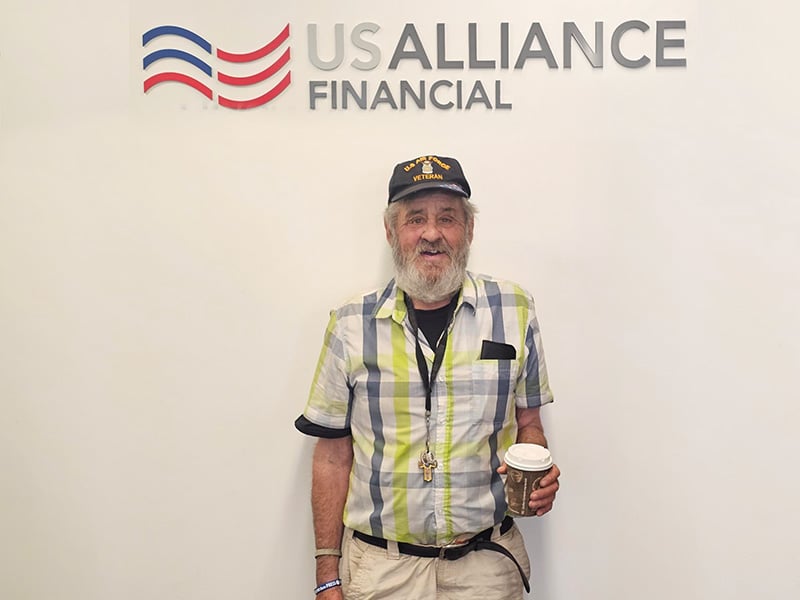 Tim, a USALLIANCE member, smiling and holding a cup of coffee
