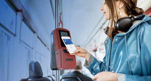 A woman scans her mobile USALLIANCE debit card to get on a city bus.
