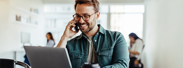 A man on the phone with his payroll provider using a laptop.