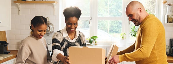 A family opens pizza boxes in the kitchen.